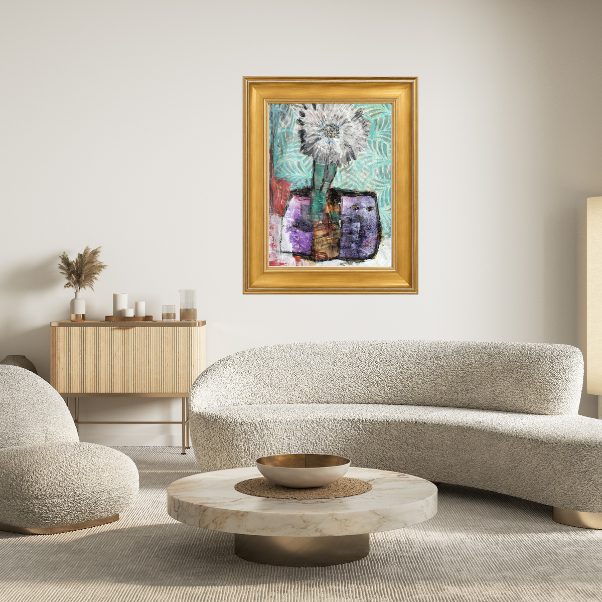 A framed abstract floral painting with a gold frame hangs on a light beige wall in a modern living room setting with a curved boucle sofa and a marble coffee table.